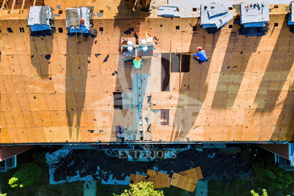 Roof Deck Maintenance Aerial view of construction workers on a wooden roof during renovation.