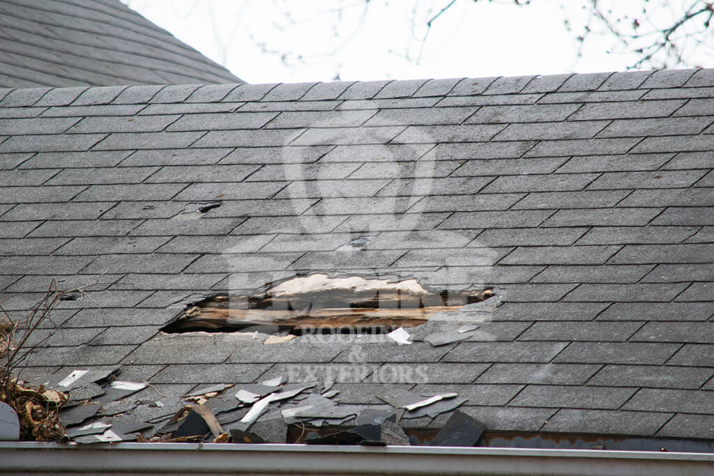 Damaged roof with large hole and missing shingles