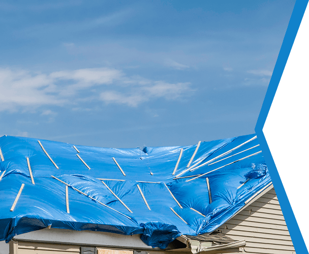 Blue tarp covering damaged roof of a house under a clear blue sky.