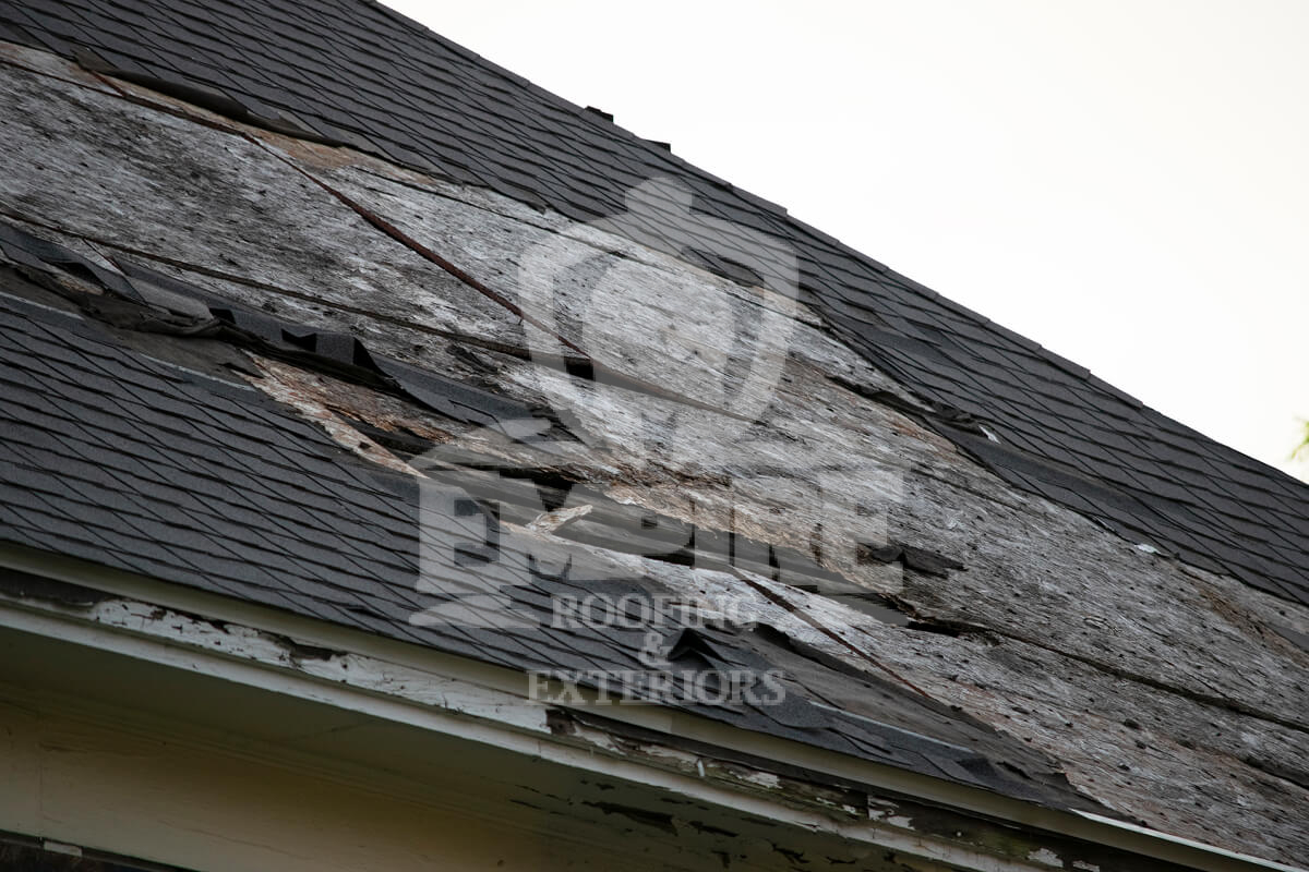 Damaged roof with missing shingles and exposed wood structure
